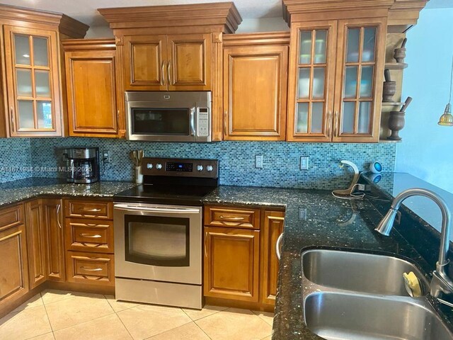 kitchen with dark stone countertops, decorative backsplash, sink, and appliances with stainless steel finishes