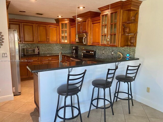 kitchen with a breakfast bar area, kitchen peninsula, decorative backsplash, and appliances with stainless steel finishes