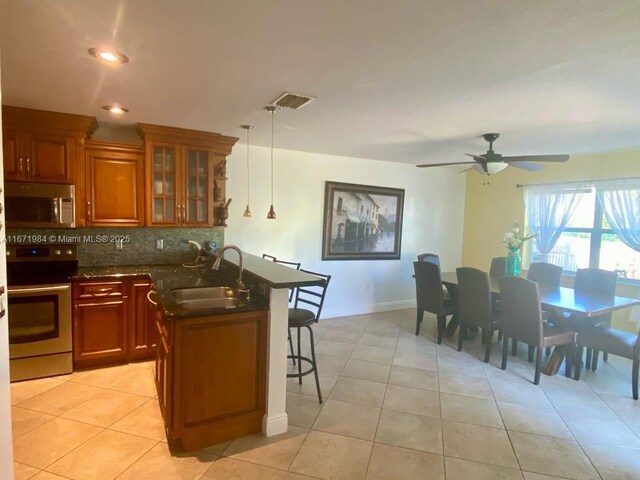 4046 Eastridge Dr, Deerfield Beach, FL 33064 - kitchen with a breakfast bar area, brown cabinetry, a sink, appliances with stainless steel finishes, and backsplash