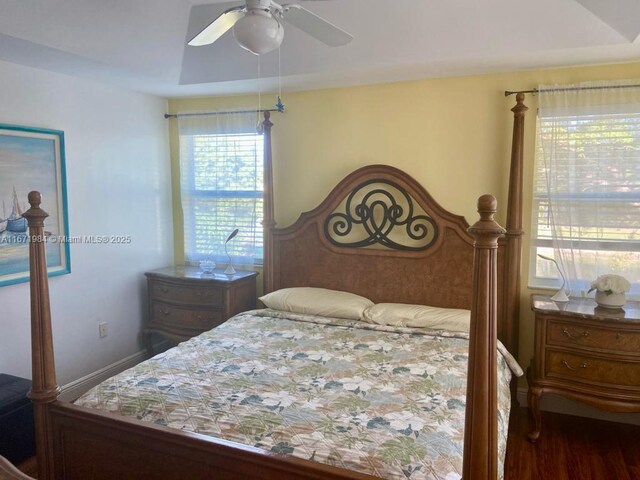 bedroom with ceiling fan, dark hardwood / wood-style flooring, and multiple windows