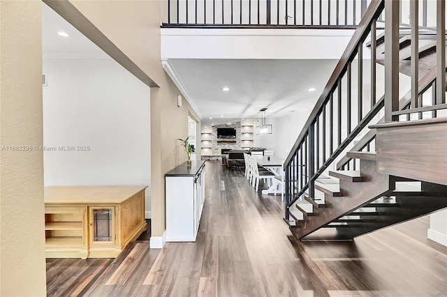 stairway featuring hardwood / wood-style flooring, ornamental molding, and a high ceiling