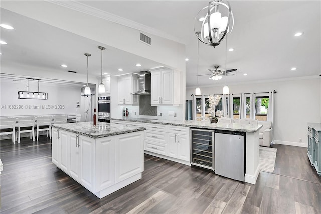 kitchen featuring wall chimney exhaust hood, white cabinetry, refrigerator, a center island, and pendant lighting