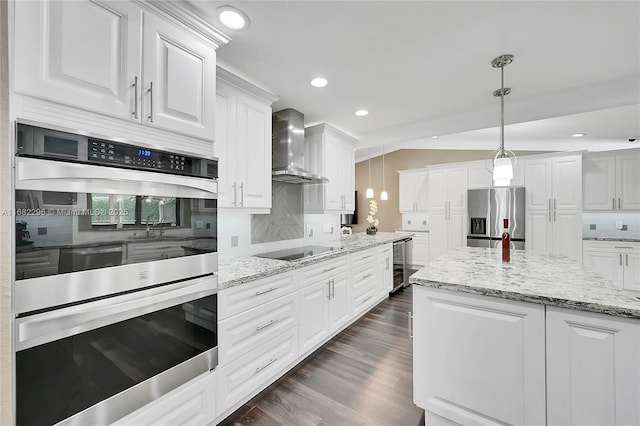 kitchen with appliances with stainless steel finishes, pendant lighting, wine cooler, white cabinets, and wall chimney exhaust hood