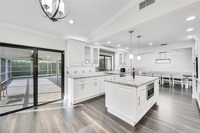 kitchen featuring light stone counters, a center island, and white cabinets