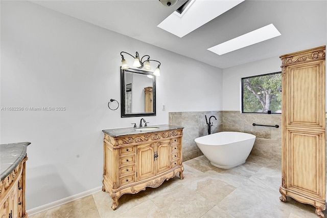 bathroom with vanity, a tub, tile walls, and a skylight