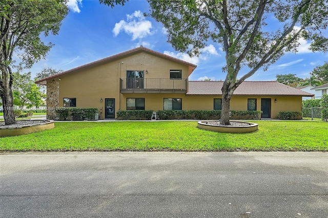 view of front facade featuring a balcony and a front lawn