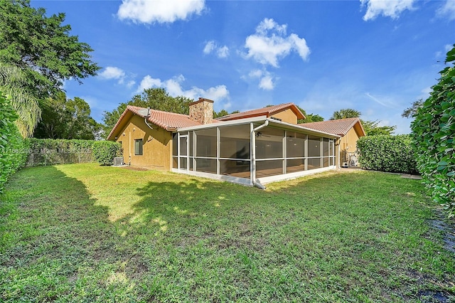 rear view of house featuring a lawn and a sunroom