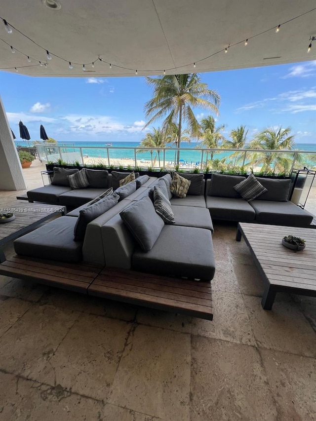 view of patio / terrace with outdoor lounge area, a water view, and a beach view