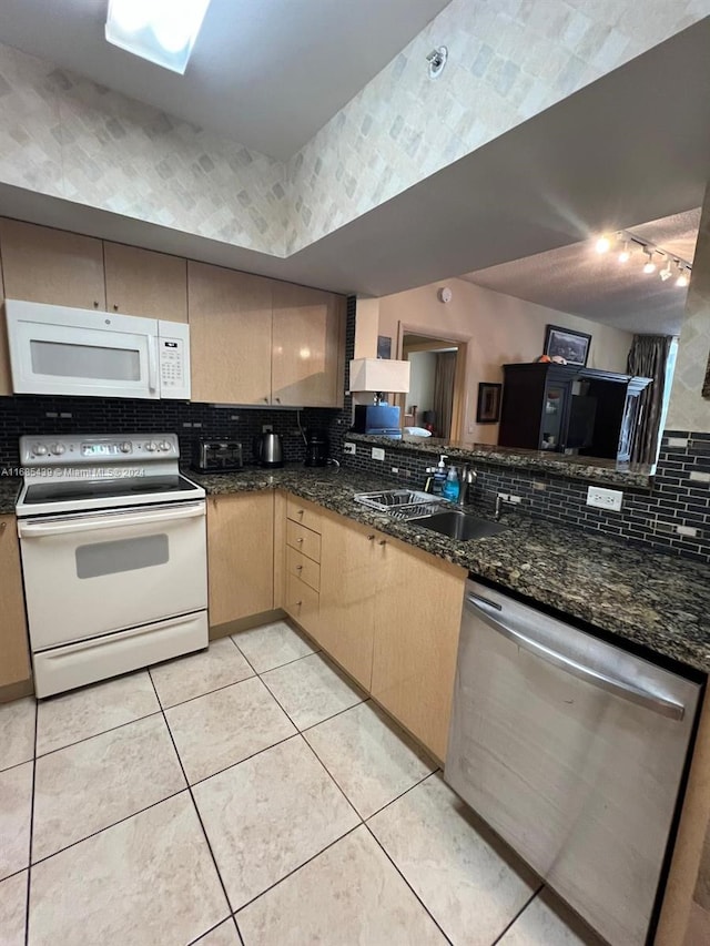 kitchen with decorative backsplash, dark stone counters, white appliances, sink, and light brown cabinets