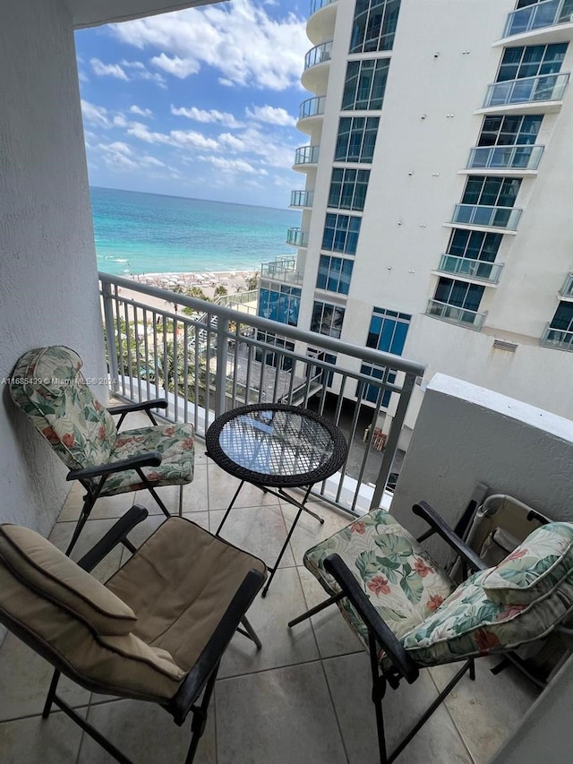 balcony with a water view and a view of the beach