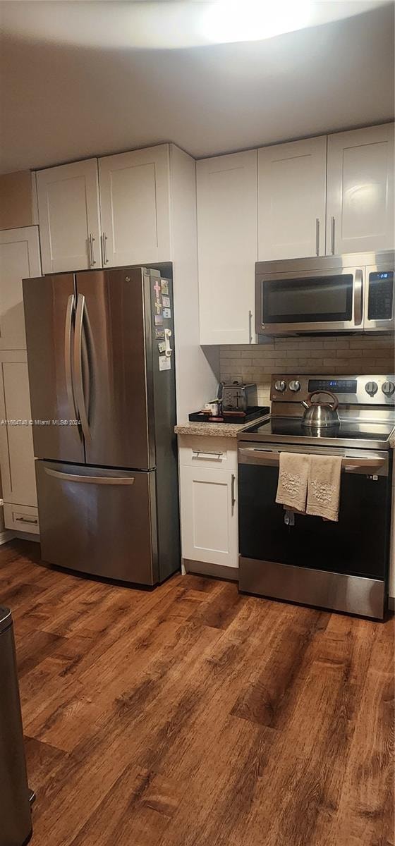 kitchen with white cabinets, stainless steel appliances, tasteful backsplash, and dark hardwood / wood-style flooring