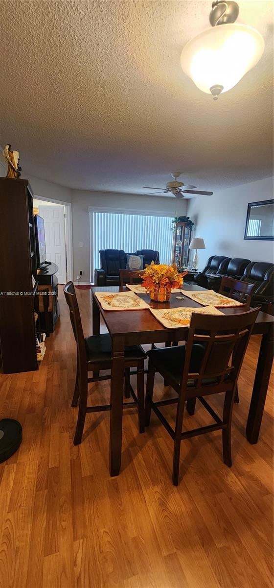 dining room with hardwood / wood-style floors, a textured ceiling, and ceiling fan