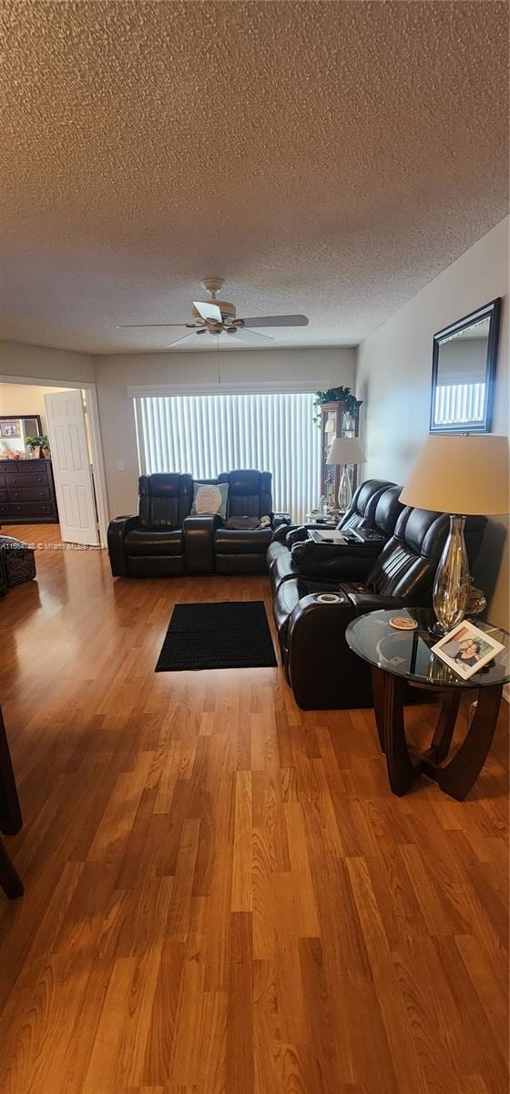 living room featuring ceiling fan, hardwood / wood-style flooring, and a textured ceiling