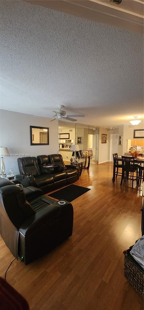 living room featuring ceiling fan, a textured ceiling, and hardwood / wood-style floors