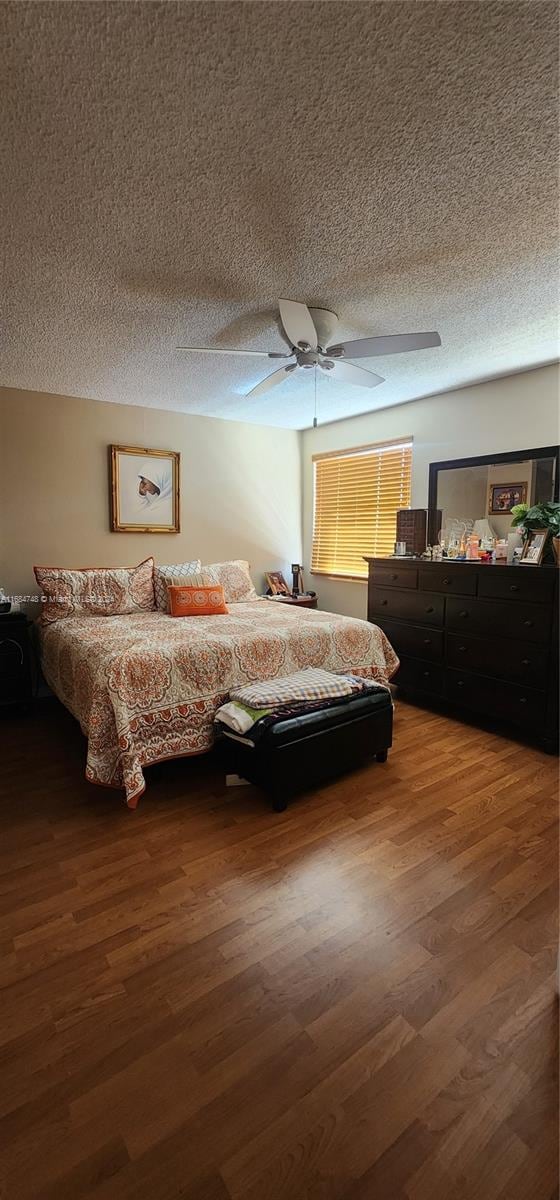 bedroom with ceiling fan, a textured ceiling, and dark hardwood / wood-style flooring