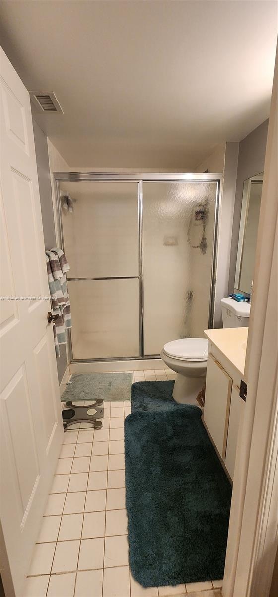 bathroom with vanity, tile patterned floors, toilet, and walk in shower