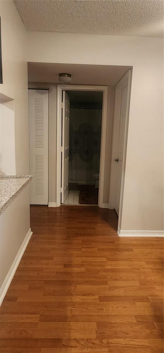 corridor featuring a textured ceiling and wood-type flooring