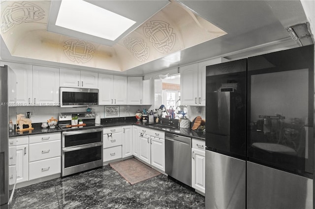 kitchen featuring lofted ceiling, white cabinets, tasteful backsplash, and stainless steel appliances