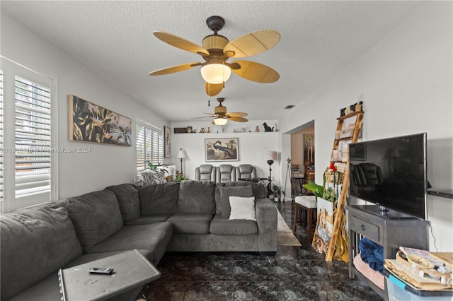 living room featuring ceiling fan and a textured ceiling