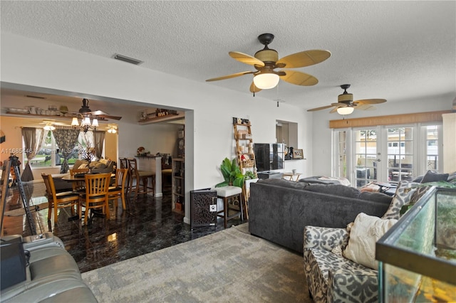 living room featuring french doors, ceiling fan, a healthy amount of sunlight, and a textured ceiling