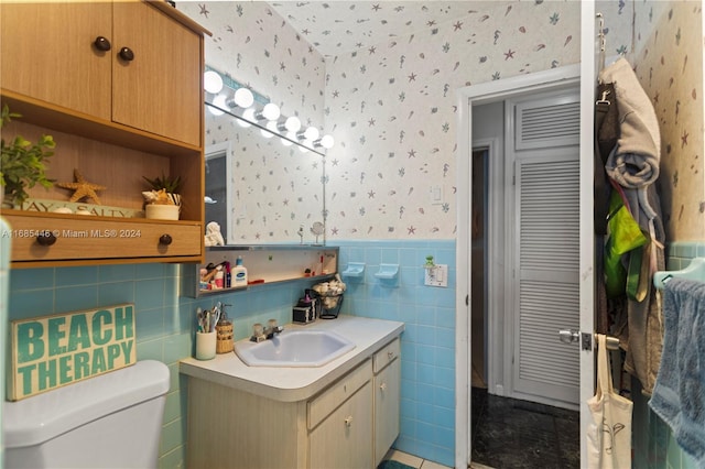 bathroom with vanity, toilet, tile patterned floors, and tile walls