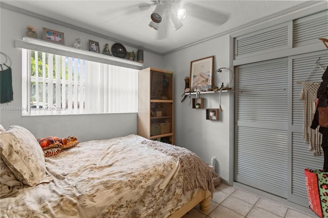 bedroom featuring light tile patterned floors, ornamental molding, a closet, and ceiling fan