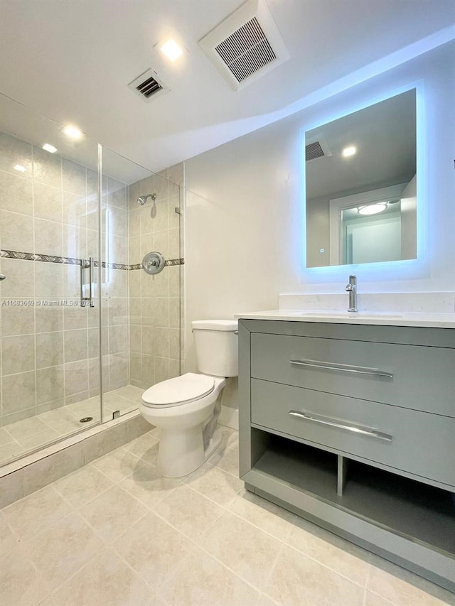 bathroom featuring toilet, a shower with shower door, vanity, and tile patterned flooring