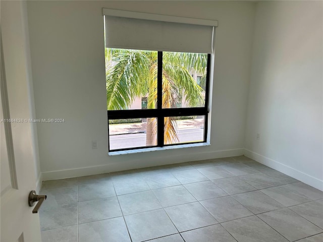 unfurnished room with light tile patterned floors and a wealth of natural light