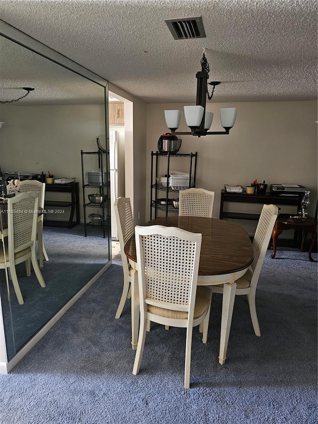 dining room featuring a notable chandelier, a textured ceiling, and carpet floors