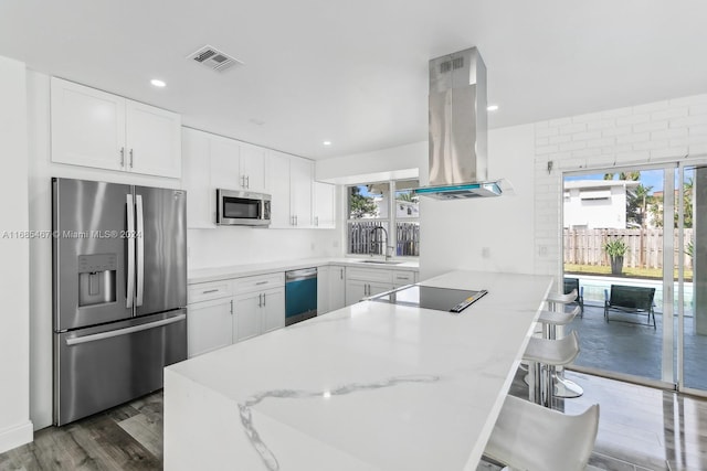 kitchen featuring a breakfast bar area, appliances with stainless steel finishes, white cabinets, and plenty of natural light