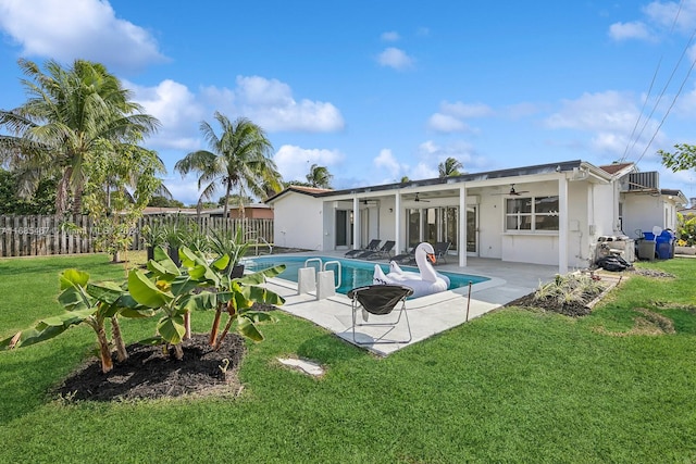 rear view of house with a patio, ceiling fan, a lawn, and a fenced in pool