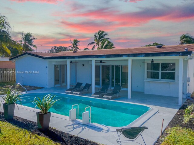 pool at dusk featuring a patio and ceiling fan