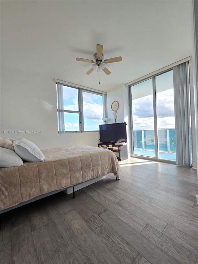 bedroom with access to exterior, hardwood / wood-style floors, expansive windows, and ceiling fan