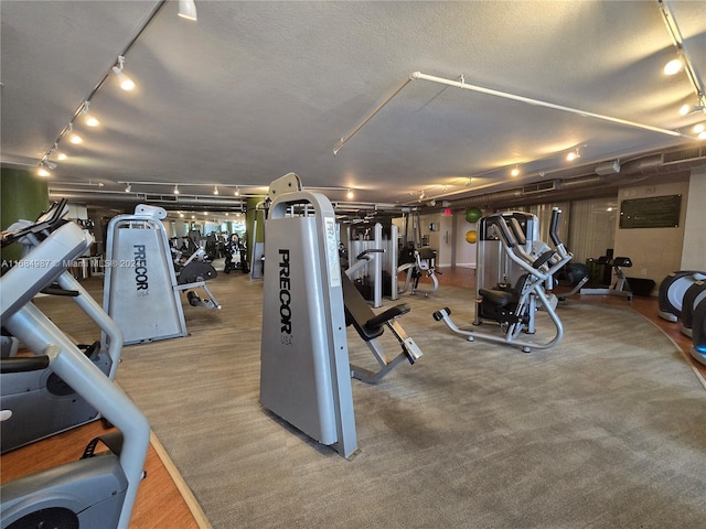 workout area with carpet floors, rail lighting, and a textured ceiling