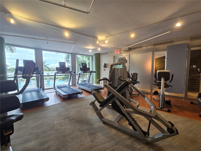 exercise room with a textured ceiling and rail lighting