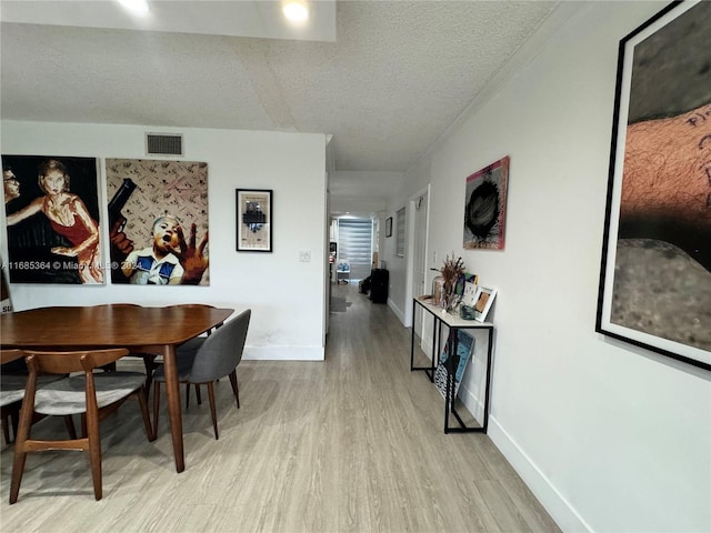 dining space featuring light hardwood / wood-style floors and a textured ceiling