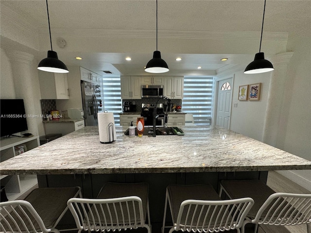 kitchen with a large island, appliances with stainless steel finishes, a kitchen bar, and pendant lighting