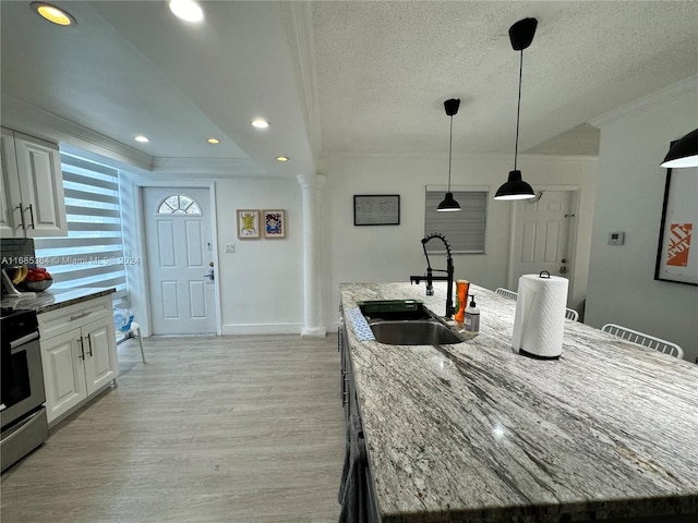 kitchen featuring a center island with sink, sink, white cabinets, and light stone countertops