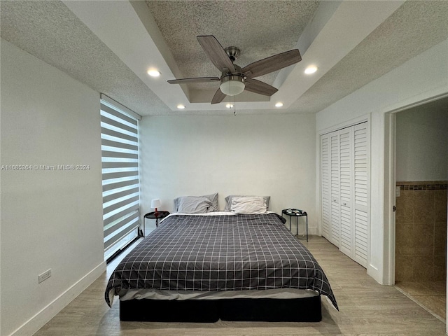 bedroom featuring light hardwood / wood-style floors, a closet, a textured ceiling, and ceiling fan