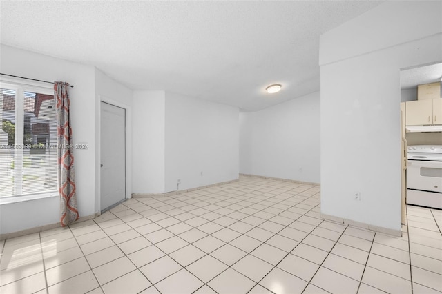 spare room with light tile patterned flooring, plenty of natural light, and a textured ceiling