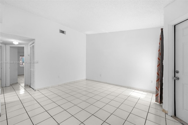 unfurnished room with a textured ceiling and light tile patterned flooring