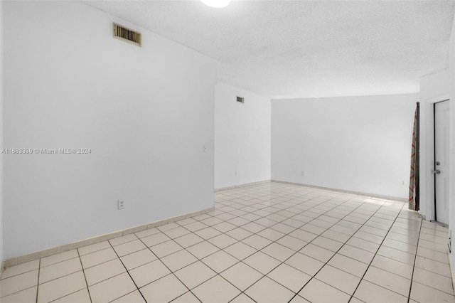 empty room featuring a textured ceiling and light tile patterned floors