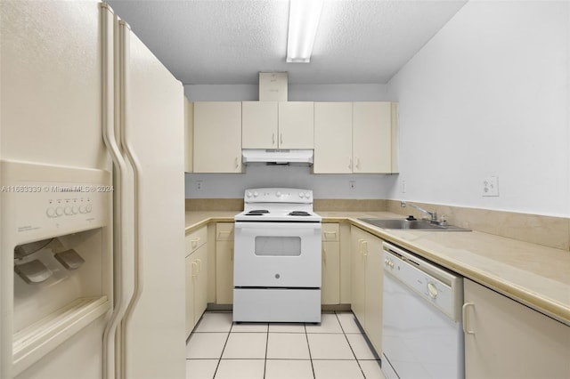 kitchen featuring cream cabinets, a textured ceiling, sink, light tile patterned floors, and white appliances