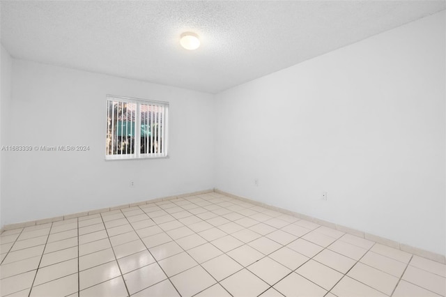 unfurnished room with a textured ceiling and light tile patterned floors