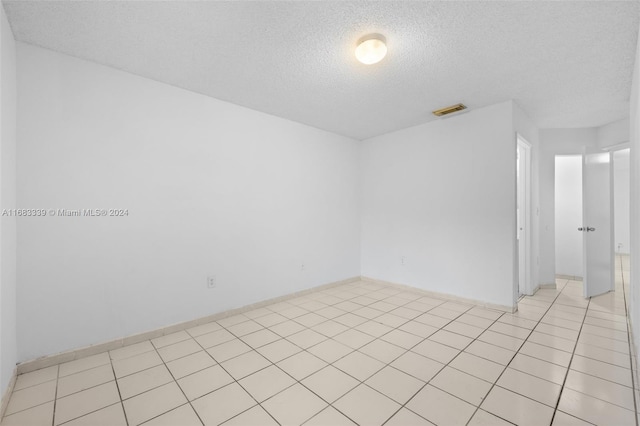 unfurnished room featuring a textured ceiling and light tile patterned floors