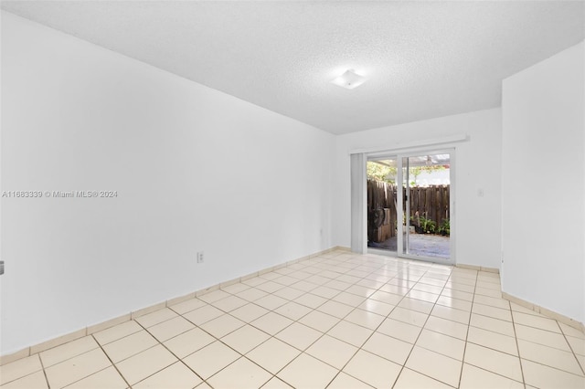 empty room with a textured ceiling and light tile patterned floors