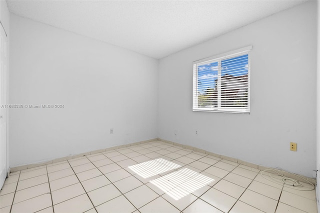 spare room with a textured ceiling and light tile patterned flooring