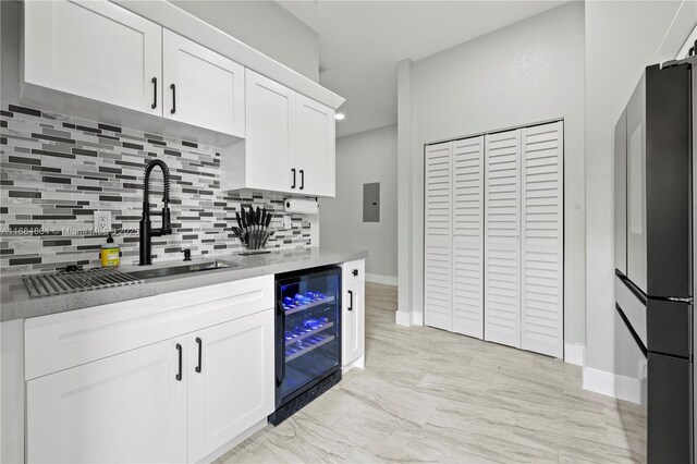 kitchen with tasteful backsplash, electric panel, white cabinets, wine cooler, and freestanding refrigerator