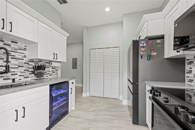 kitchen featuring beverage cooler, decorative backsplash, range, and white cabinets