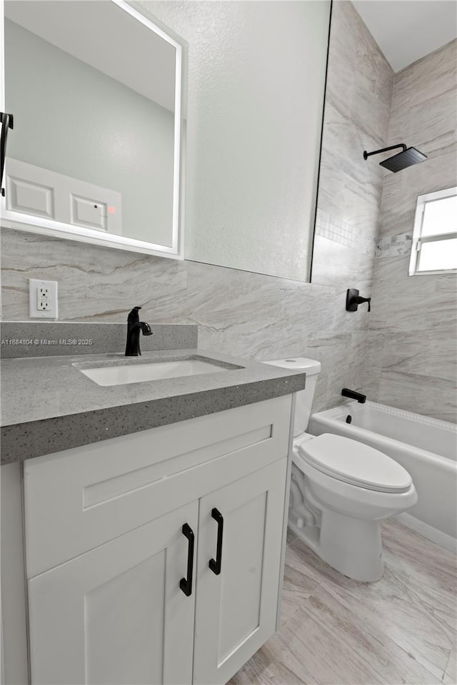 full bath featuring toilet,  shower combination, tile walls, and vanity